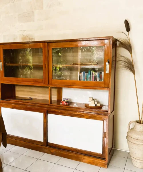 Wooden cabinet with books and Balinese decor in the guest lounge