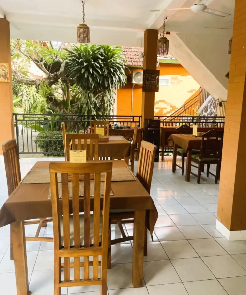 Wooden dining tables beside the tropical garden at Kubu Elsa Bali