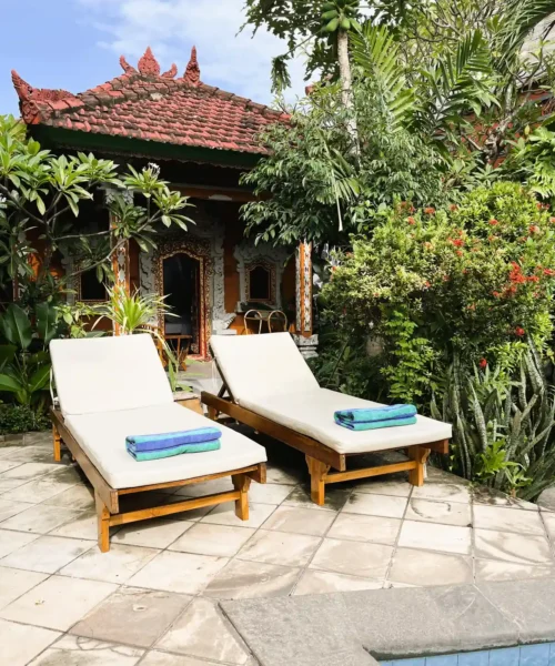 Poolside sunbeds with folded towels and tropical garden views