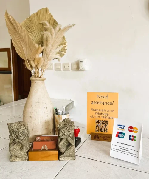 Balinese statues, payment information and guest assistance sign at reception